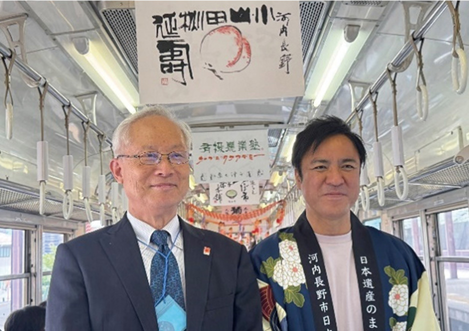 「大阪産（もん）河内長野市×小山田の桃」の広告と河内長野市西野市長と小山田の桃の書を揮毫した書家真鍋井蛙先生